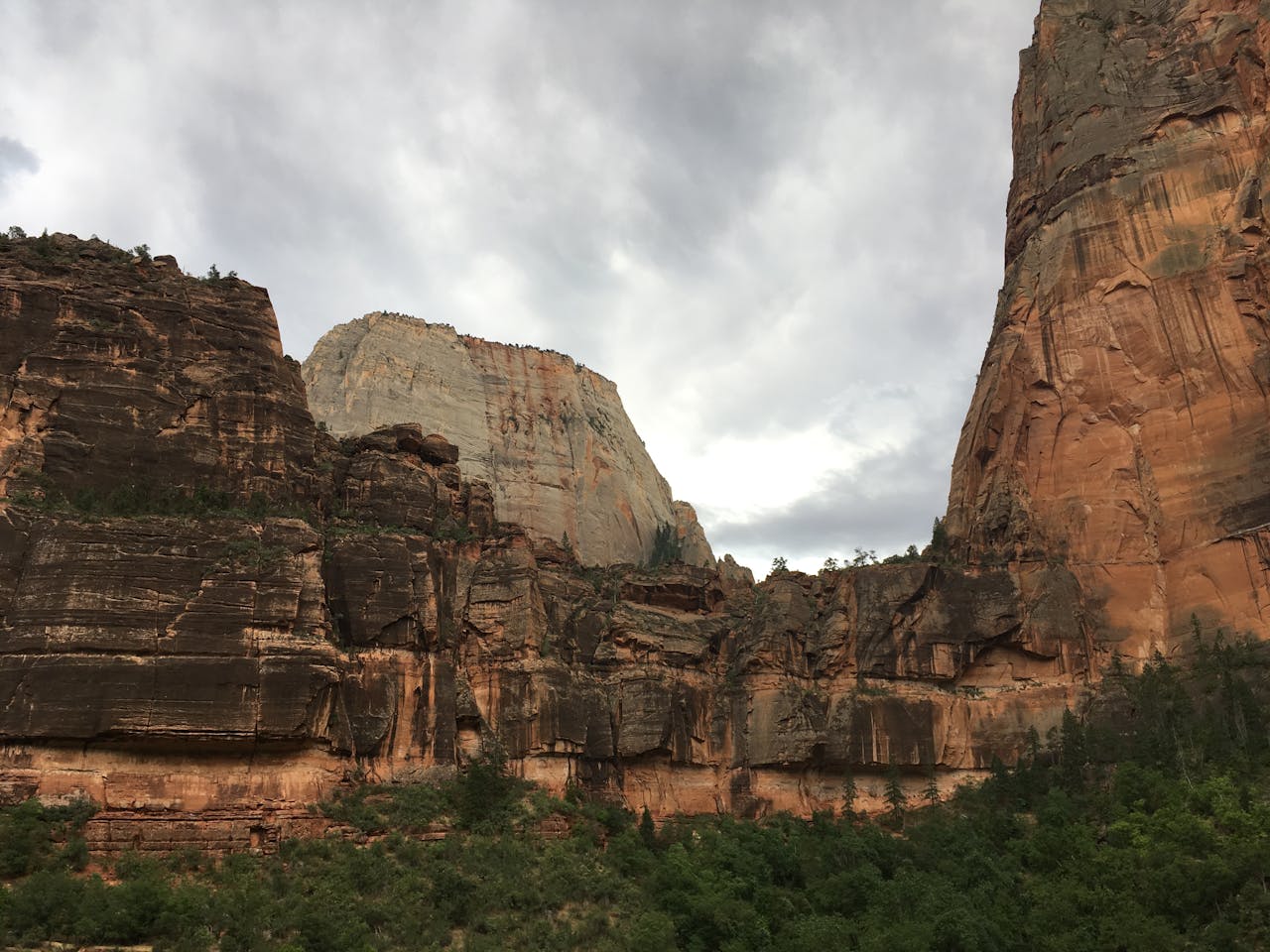 services-03 Majestic cliffs of Zion National Park against a cloudy sky, showcasing rugged natural beauty.